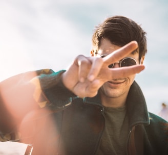 shallow focus photography of smiling man doing peace sign